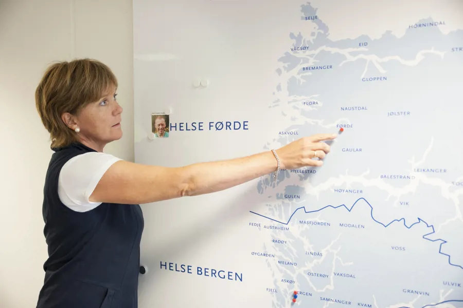 Kvinne peker på kart over Vestland fylke med Helse Førde og Helse Bergen. Foto