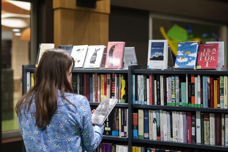 En kvinne som ser på bøker på en hylle