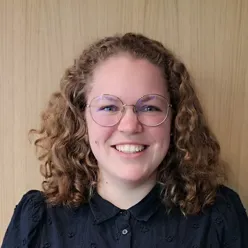 En person med krøllete hår som smiler