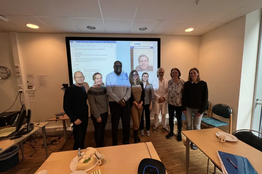 Group photo in front of screen i meeting area. Photo