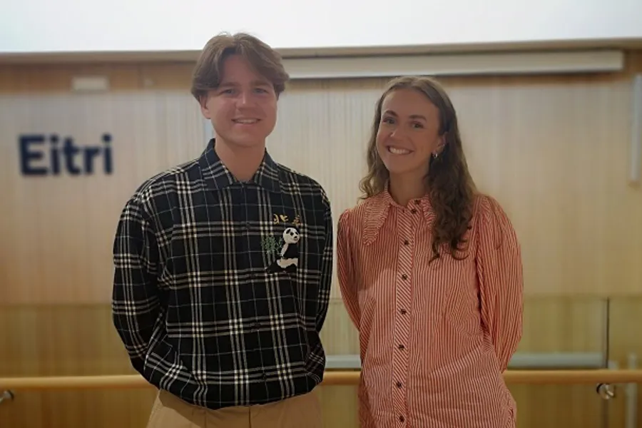 Young man and woman smiling and standing in front of the sign Eitri. Photo