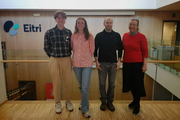 Group of people smiling and standing in front of the sign Eitri. Photo