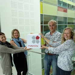 Fire ansatte ved NAPOS holder en boks med logo