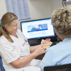 Sykepleier med modell av kvinnelig underliv forklarer pasient. Foto