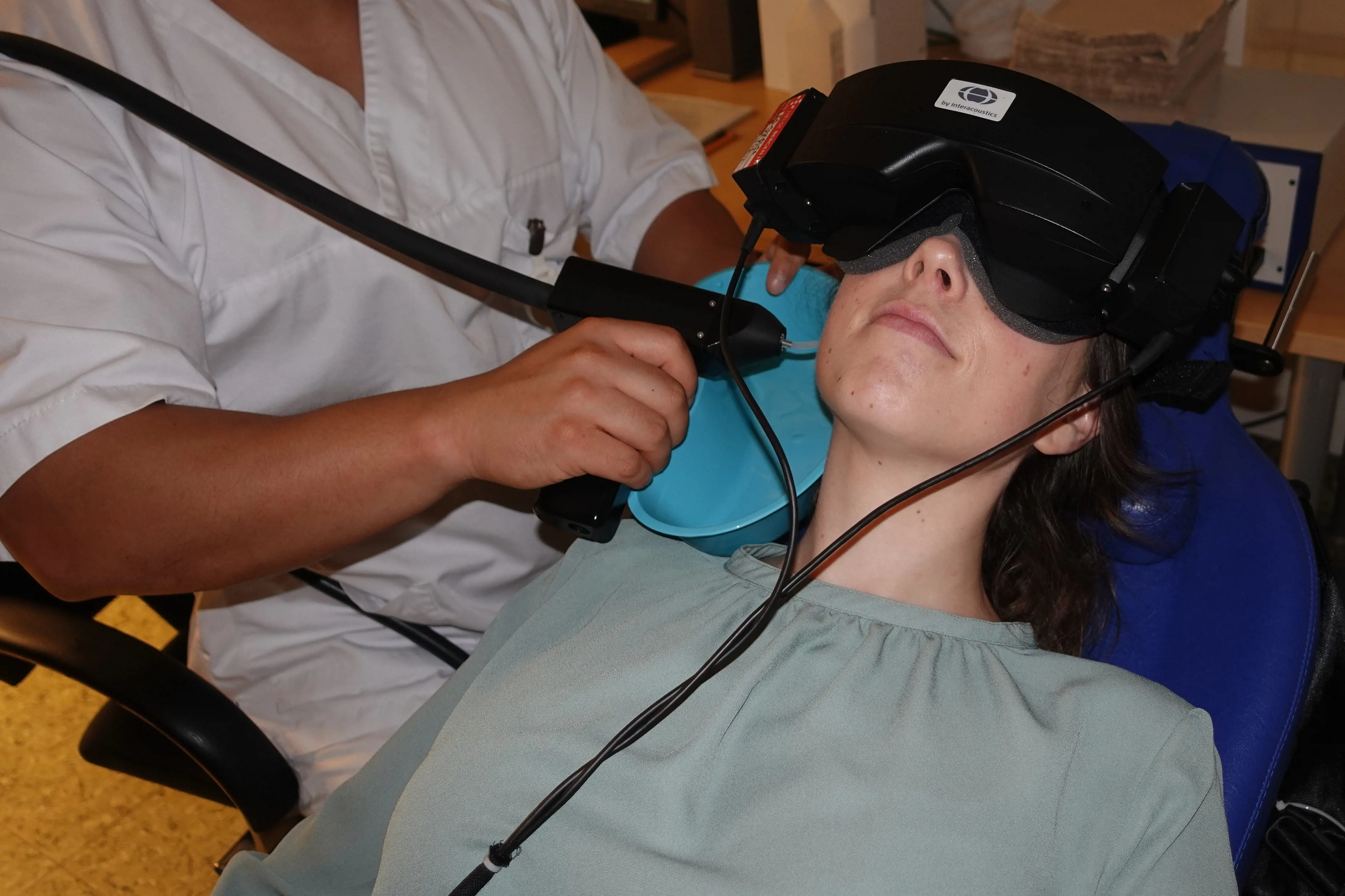 Helsepersonell undersøker kvinnelig pasient som ligger med videobriller på seg. Foto