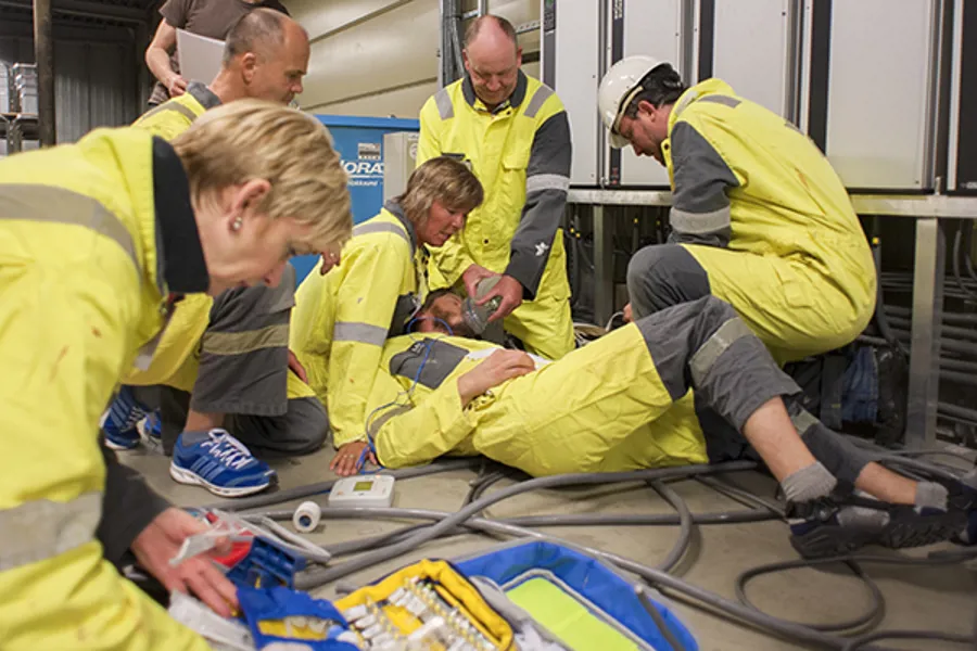 En gruppe mennesker i gule jakker som jobber på en maskin