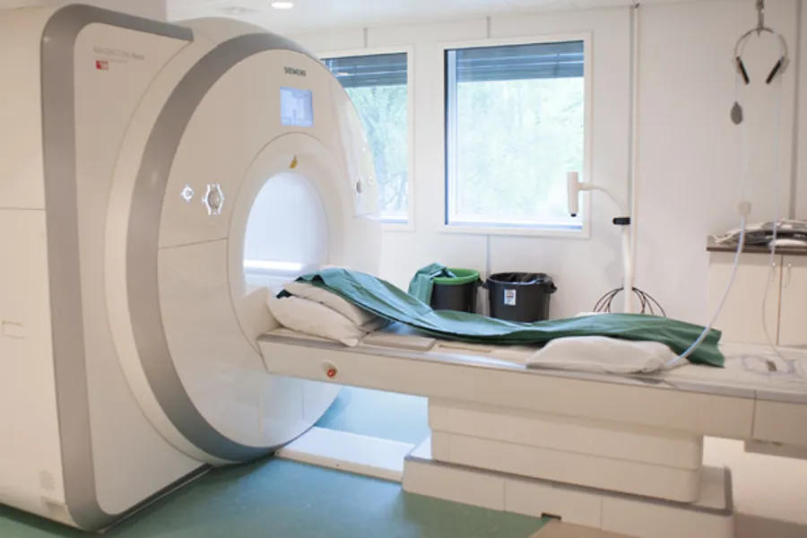 MR-maskin med pasientbenk og grønt laken i undersøkelsesrom. Foto