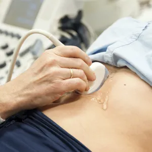 Kvinne ligger på undersøkelsesbenk og blir undersøkt med ultralyd. Foto