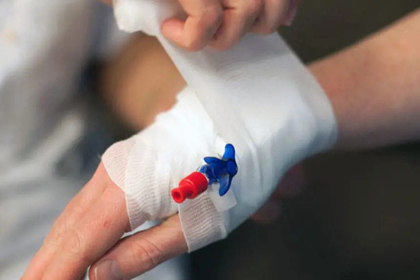 Sjukepleiar tar støttebandasje på hand med venflon. Foto