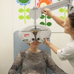 Kvinnelig ansatt justerer maskin foran øynene til kvinnelig pasient.