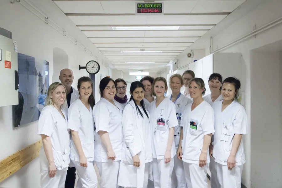 Gruppebilde av sykehusansatte i korridor på sengepost. Foto