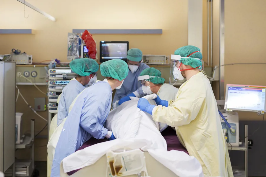 Intensivsykepleiere i smittevernutstyr arbeider rundt sengen til pasient. Foto