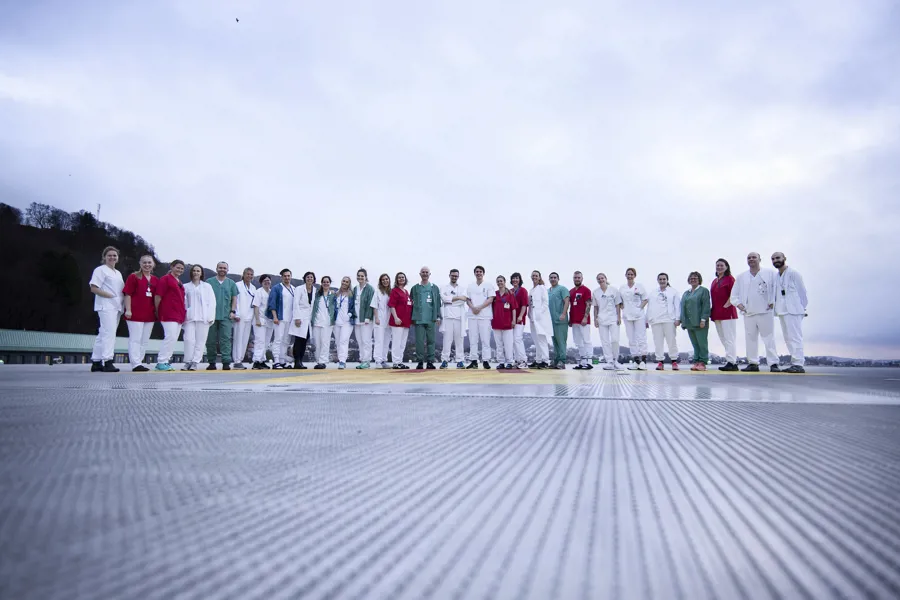Helsepersonell i forskjellige uniformer stilt opp i rekke på helikopterdekket til Haukeland. Foto