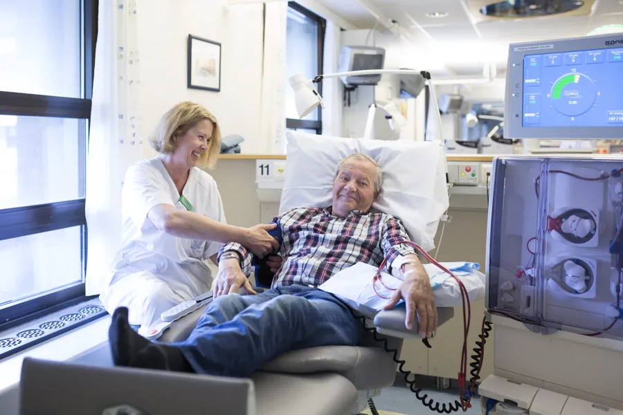 Sykepleier og eldre mannlig pasient til dialysebehandling. Foto