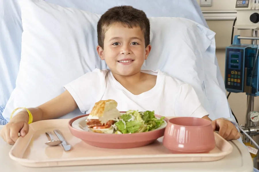 gutt spiser mat i sykehusseng