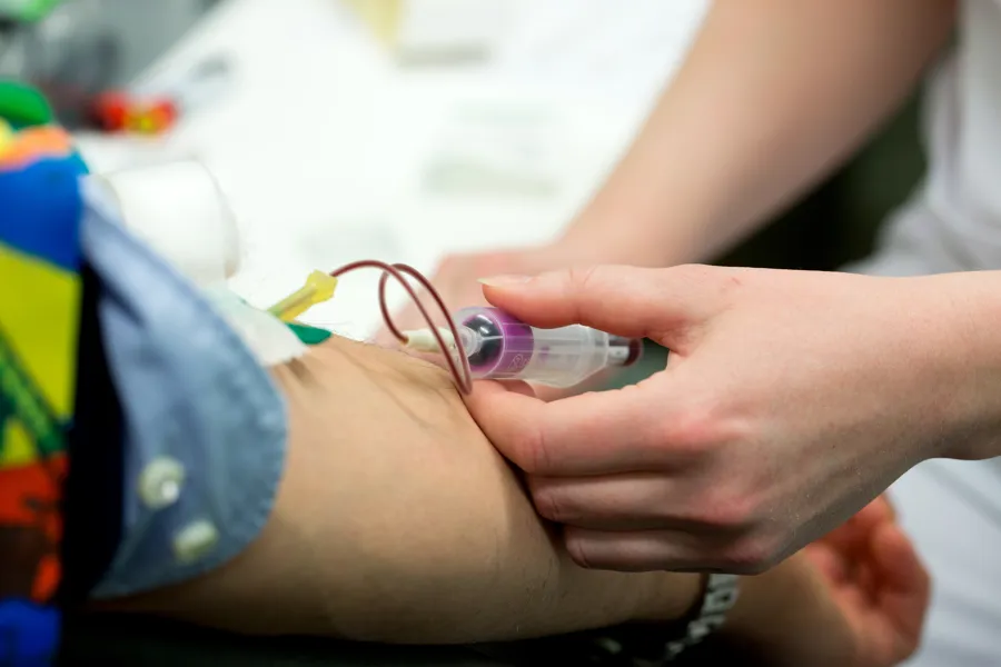 Helsepersonell tar blodprøver av person med kanyle i armen. Foto