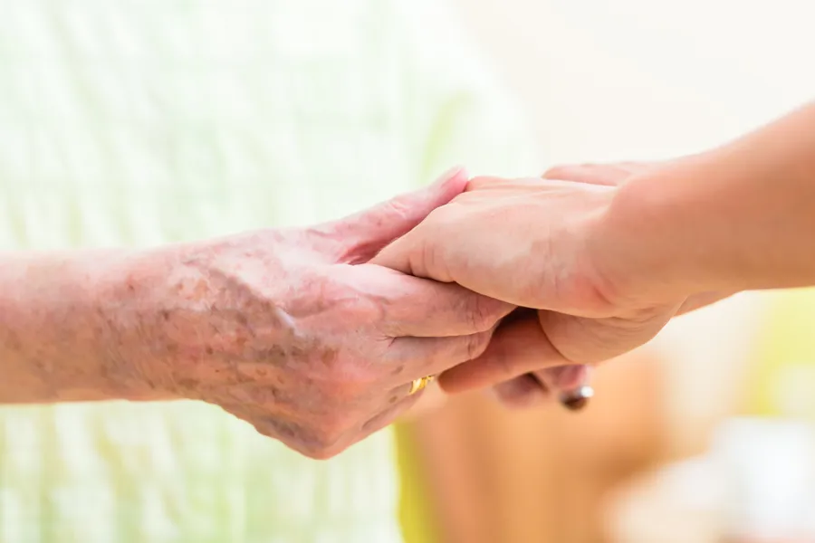 Eldre par hender holder i yngre hender. Foto