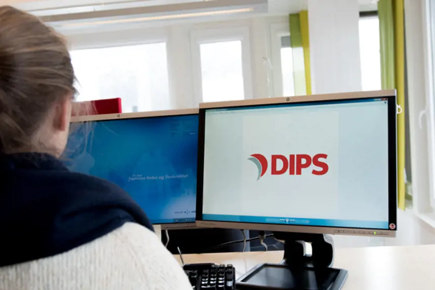 Ansatt foran PC-kjerm med DIPS-logo på skjermen. Foto