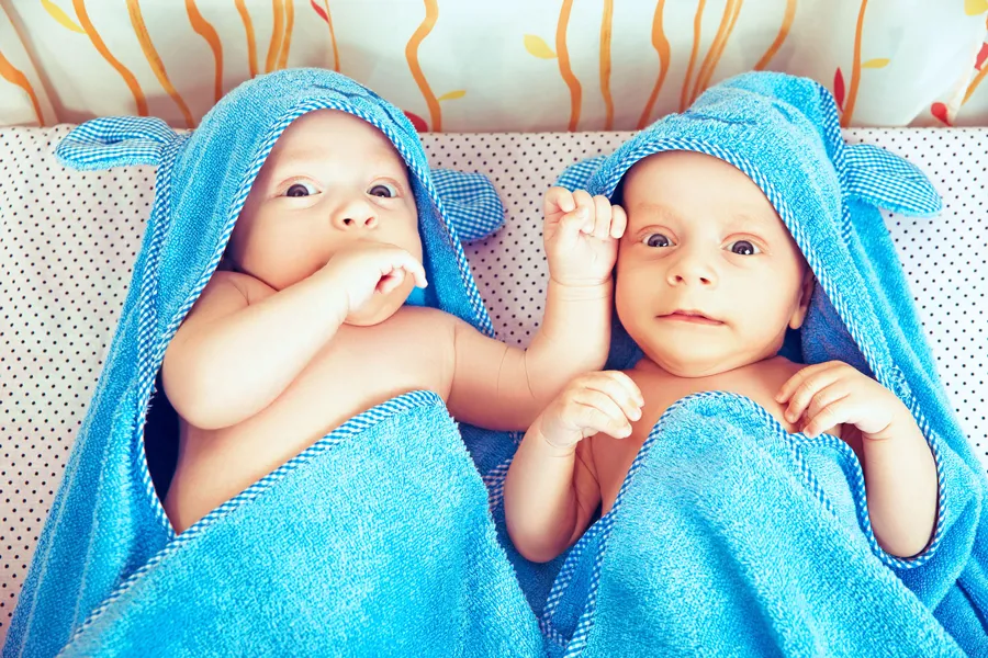 Tvillingbabyer i badehåndkle. Foto