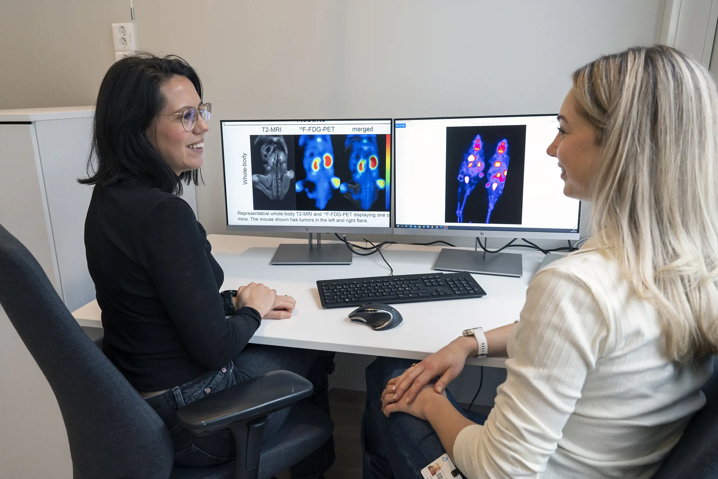 To forskere foran to dataskjermer med MR- og PET-bilder. Foto