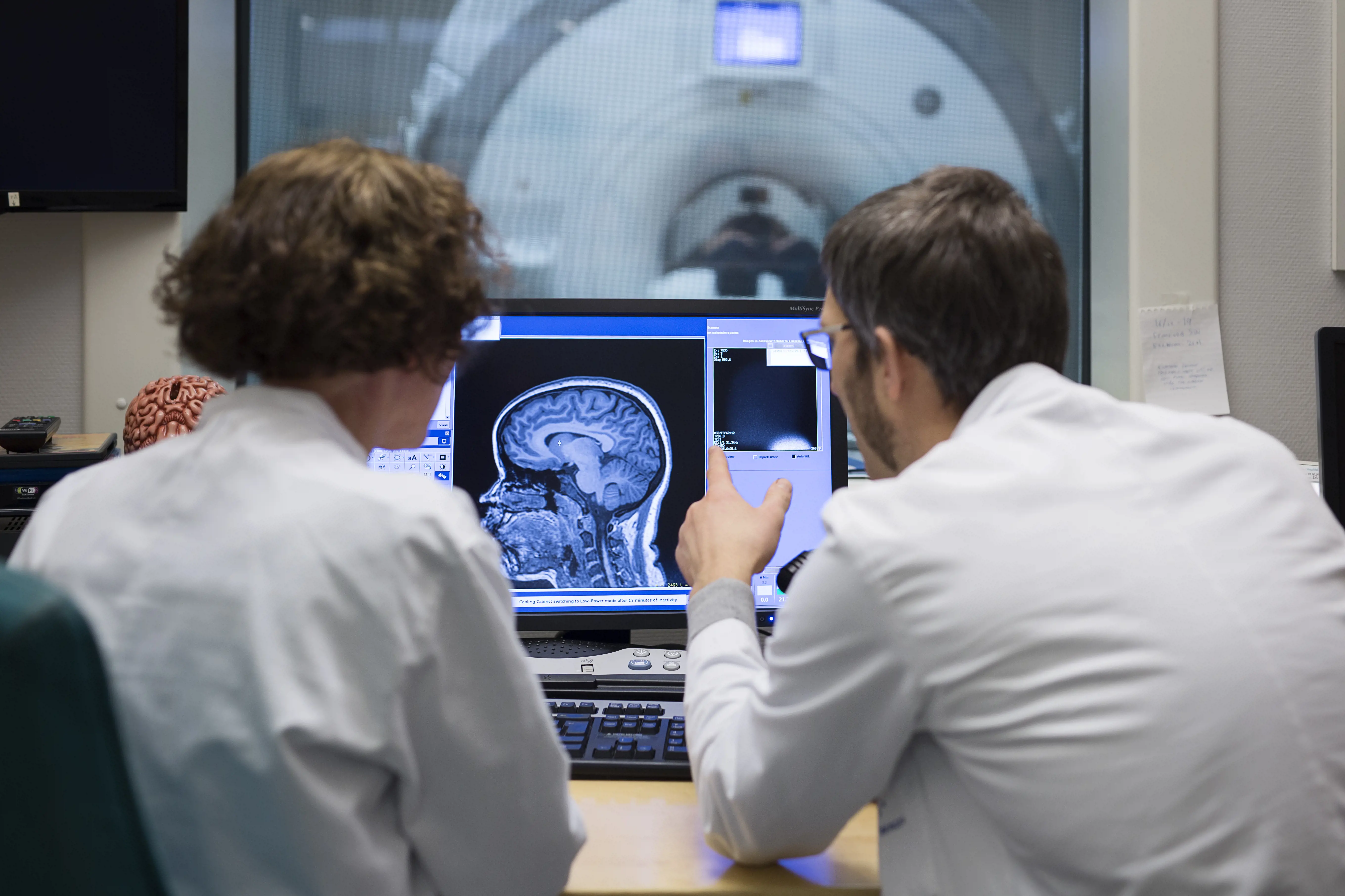 Foto:To ansatte sitter og ser på en skjerm som viser røntgenbilde av hodet