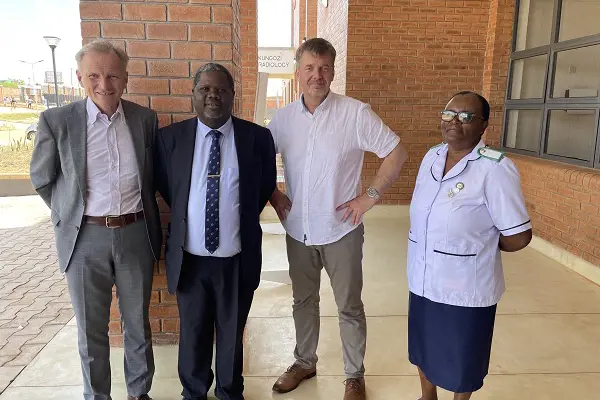 Tre menn og en kvinne foran sykehusbygg i Malawi