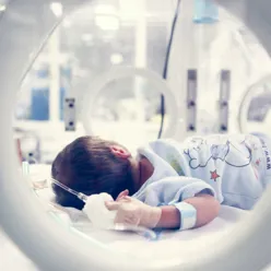 En baby som ligger i en inkubator