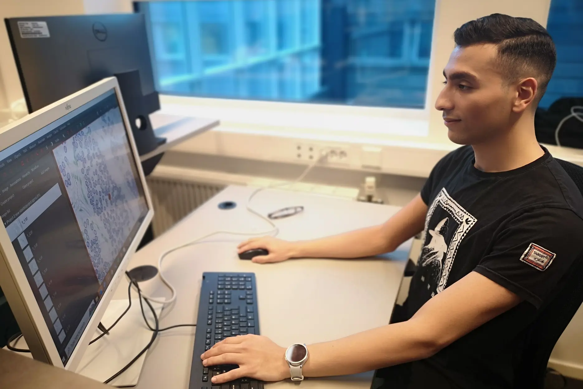 En mann som sitter ved et skrivebord med en datamaskin og et tastatur