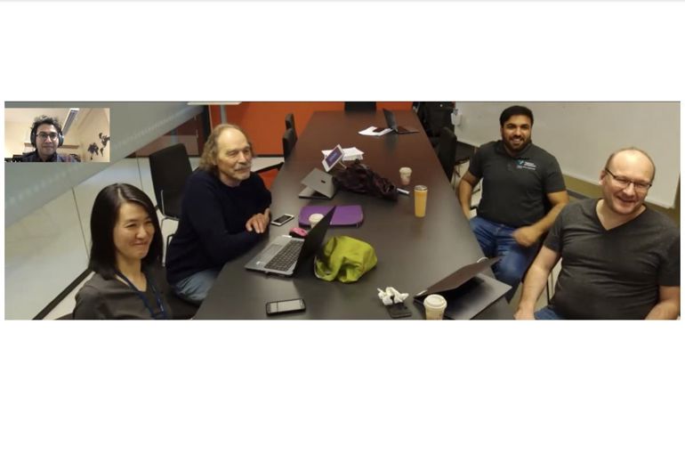 En gruppe mennesker som sitter rundt et bord med en bærbar datamaskin