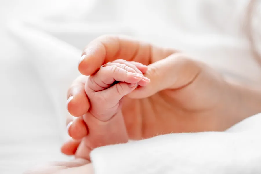 En voksen hånd som holder en babyhånd