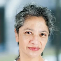 Portrett Leslie Eide, kvinne med håret satt opp og kledd i hvit helsepersonelluniform.