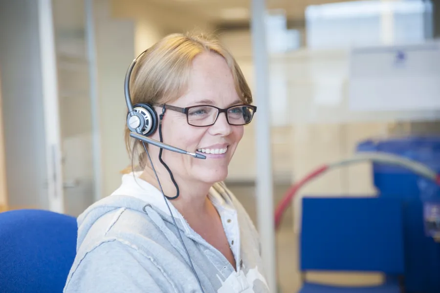 Smilende ansatt med telefonheadsett. Foto