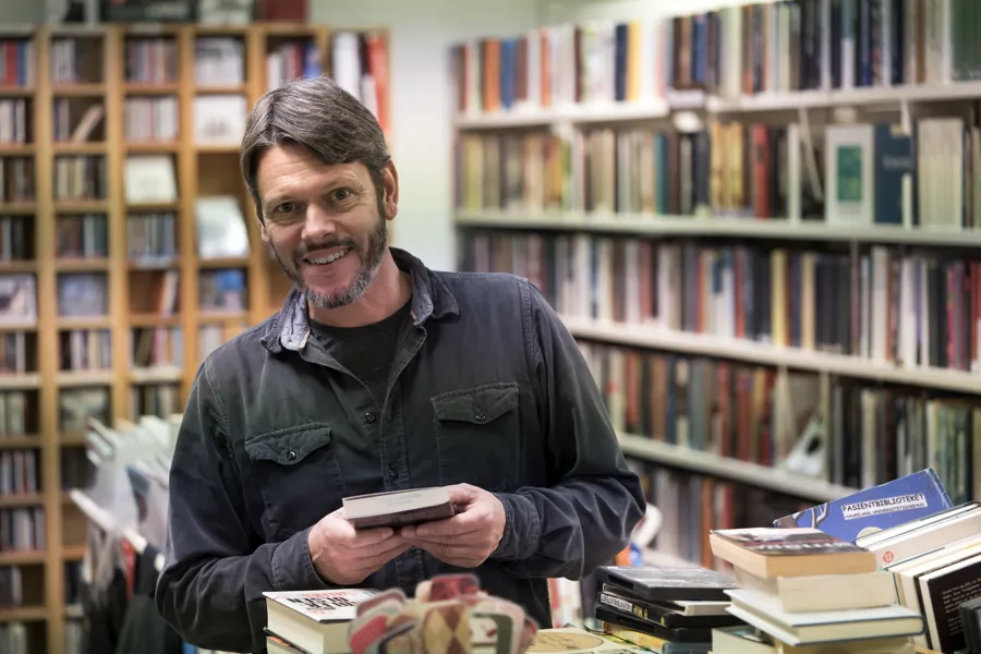 bibliotekaren står foran bokhyller med bok i hånden. foto.